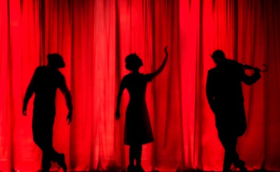 Rideau rouge et trois silhouettes de comédiens